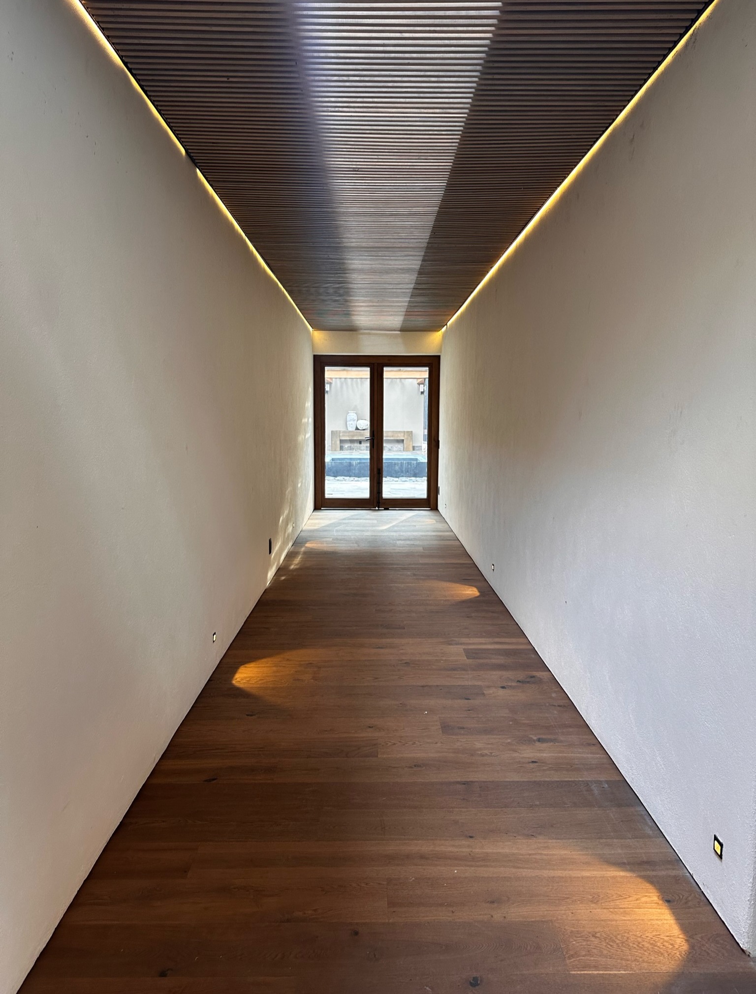 Pasillo con piso de madera y puerta de madera