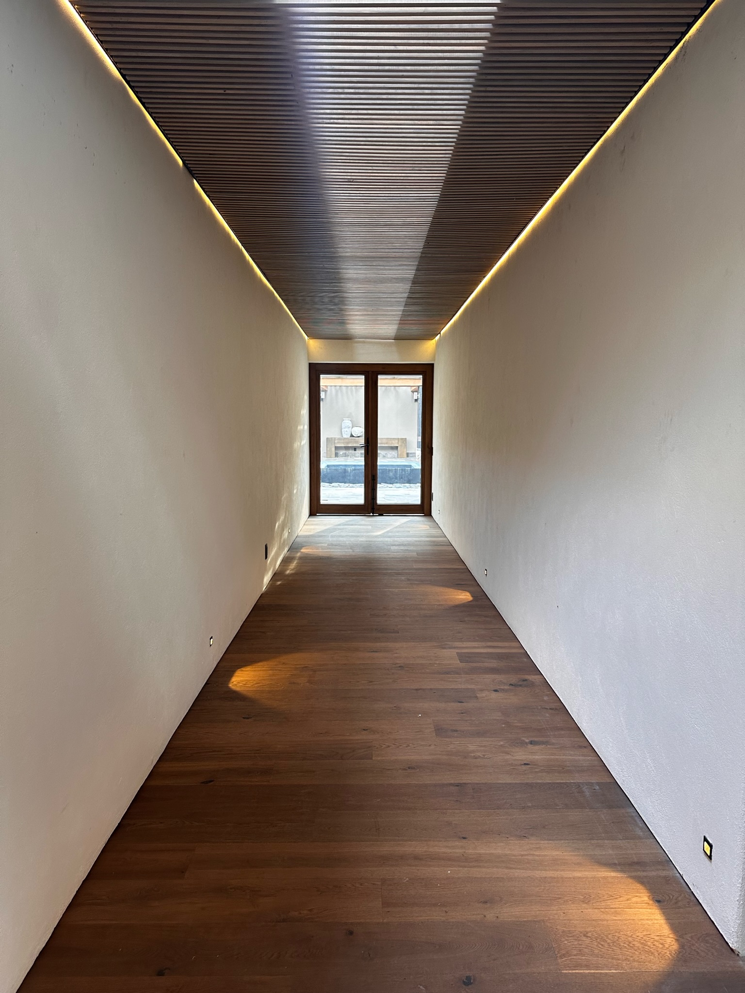 Pasillo con piso de madera y puerta de madera